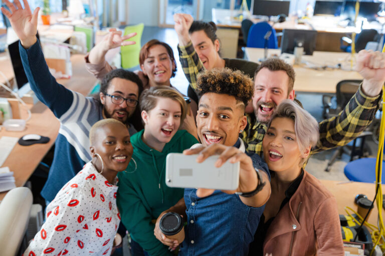 Team talking group selfie with smartphone in office