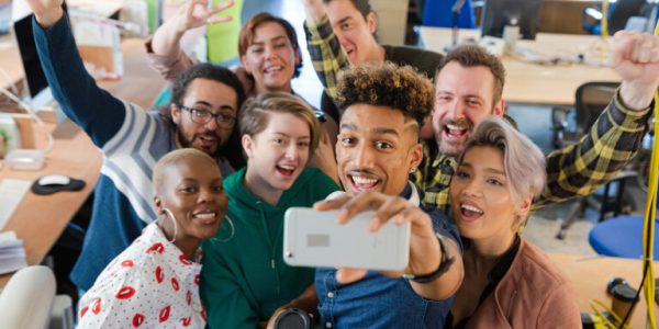 Team talking group selfie with smartphone in office